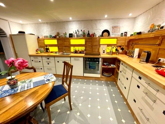 Wohnküche im Bauernhaus mit Holztisch, Kochzeile und Fliesenboden